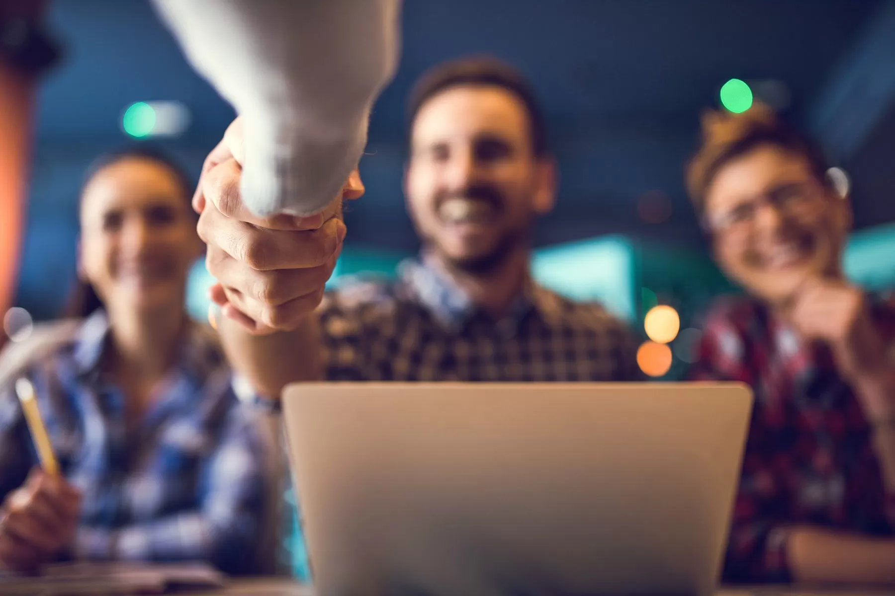 3 happy people shaking hands